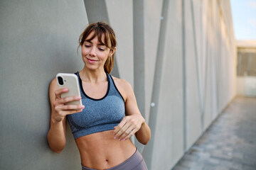 Woman in sportswear checks phone while enjoying outdoor fitness activity