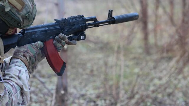 Soldier fires a suppressed tactical rifle. Concept for modern warfare, special forces, and security operations.