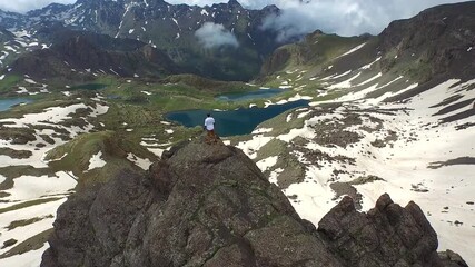 Successful businessman celebrates victory on snowy mountain peak. The triumphant person stands on the rocky summit, symbolizing accomplishment and high elevation goals.