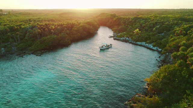Boat anchored in narrow tropical lagoon with dense jungle in Mexico at sunset