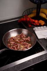 sizzling bacon in a pan on modern kitchen stove with fresh tomatoes and assortment of fruits in basket, creating a cozy culinary atmosphere, comfort, aroma, vibrant, domestic, appetizing, household