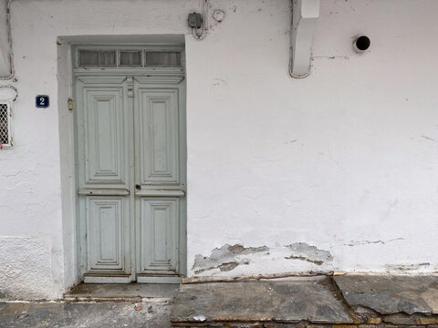 Weathered wooden door on rustic white building exterior