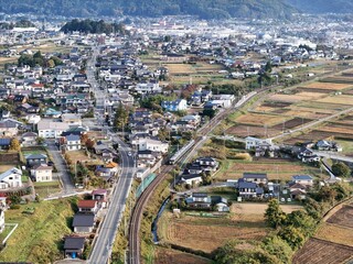 Fototapeta premium A city with a train track running through it. The train is green and is in the middle of the track. The city is full of houses and buildings