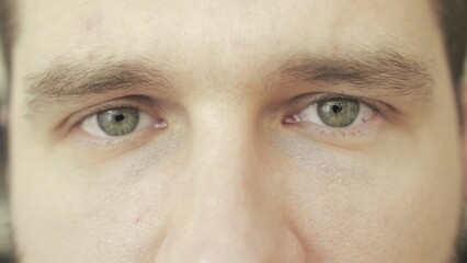 Close up of young man thinking about something, looking at camera. Slow motion