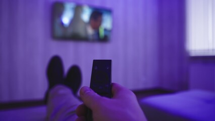 Man watching TV with remote control in hand, lying on the sofa. Slow motion