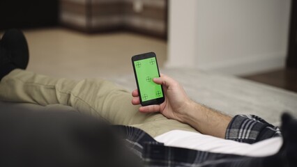 Male hands texting on phone screen at home. Green mock-up screen. Slow motion