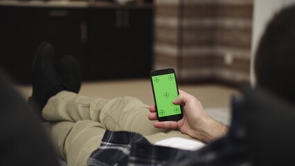Young man scrolling and touch clicking on the screen. Green mock-up screen