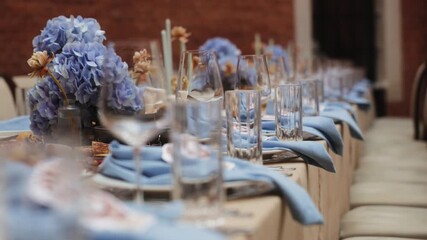 Elegant table setting with blue napkins and glassware, close-up of wedding or festive dinner decor with floral accents, luxury event preparation and celebration atmosphere concept