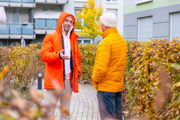 Two men chatting on paved autumn path near modern apartment buildings, arguing on a city street, emotional conversation, relationship tension, Generational dialogue outdoors, Autumn emotions