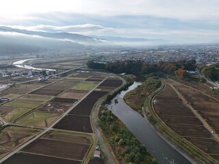 A view of a river with a city in the background. The city is mostly empty, with only a few buildings visible. The river is calm and peaceful, with trees lining its banks. Scene is serene and tranquil