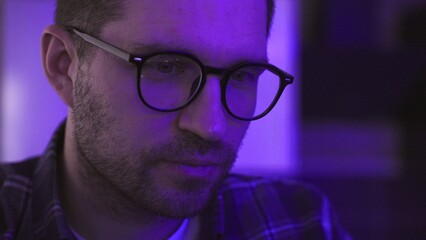 Smiling young man in eyeglasses enjoying dj party show online. Slow motion