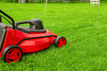 Fototapeta premium A lawnmower stands on the lawn in the garden.
