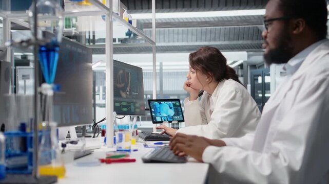 Diagnostic laboratory manager overseeing scientists looking at molecular models on PC. Team leader supervising researchers using bioengineering program on computer in medical lab, camera A