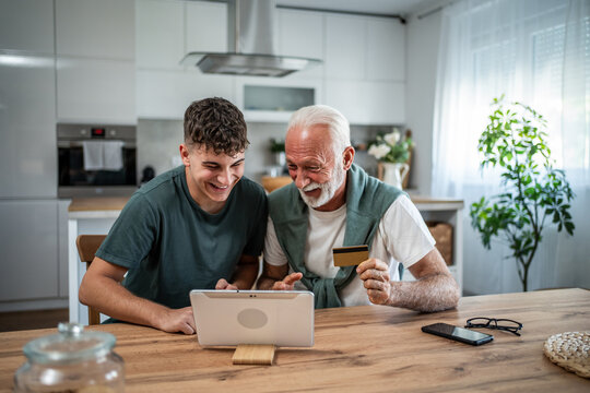Grandfather grandson online shopping using credit card on tablet