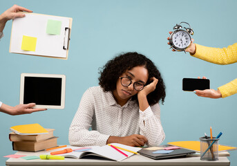 Young black woman sits at her desk feeling tired and overwhelmed. Hands reach out with a clock,...