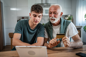 Grandfather and grandson online shopping with credit card and tablet