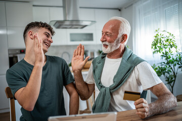 Obraz premium Grandfather and grandson high-fiving celebrating successful online shopping