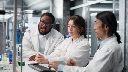 Diverse team of research facility professional using PC software to evaluate genetic marker associated with disease risk. Multiracial coworkers study DNA strand mapping, camera B - Powered by Adobe