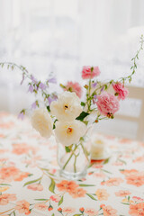 Elegant light flowers in a clear glass vase on soft background, minimal floral composition with bright petals and natural aesthetic home decor