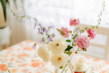 Elegant light flowers in a clear glass vase on soft background, minimal floral composition with bright petals and natural aesthetic home decor
