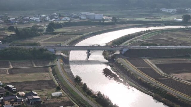 A river with a bridge over it and a town in the background. The bridge is a large structure that spans the width of the river