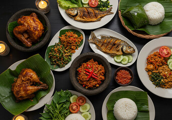 A top-down view of a diverse Indonesian feast, featuring grilled fish, chicken, rice, and various spicy side dishes.