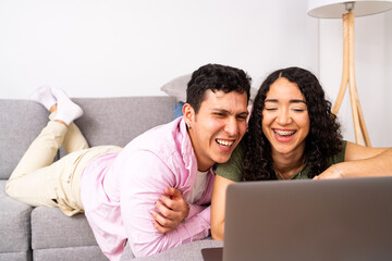Fototapeta premium Young couple laughing enjoying digital content on laptop