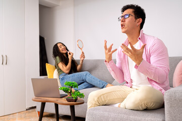 Young couple arguing in living room, woman applying makeup