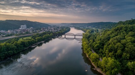 Fototapeta premium Scenic Aerial View of a Tranquil River Flowing Through Lush Greenery with a Bridge and Distant City