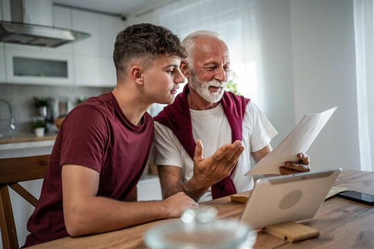 Grandfather teaching grandson about finances and paperwork at home