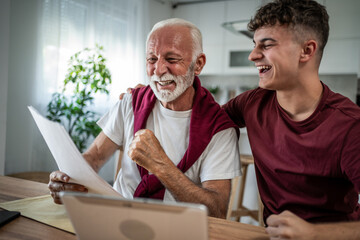 Grandfather and grandson celebrating success reading documents