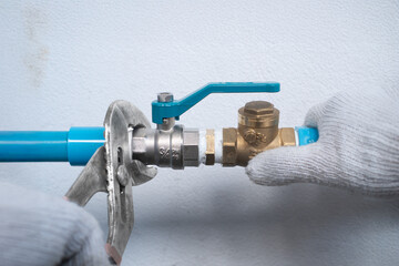 Plumber tightening nipple fitting with pipe wrench on home water pump system