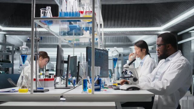 Lab microbiologist using scientific microscope for cellular analysis, writing down information. Research facility expert using optical device gear to examine medical samples, taking notes, camera A