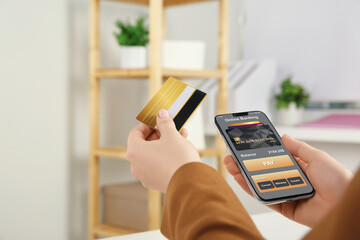 Woman with credit card using smartphone for online payment indoors, closeup