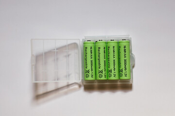 close up row of NiMH AA rechargeable batteries on transparent plastic box isolated on white...