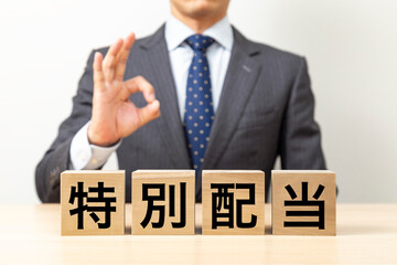 Obraz premium 「特別配当」と書かれたブロックとOKポーズをするビジネスマン