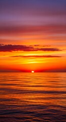 Obraz premium Vibrant sunset over rippling ocean water with dramatic orange and purple clouds