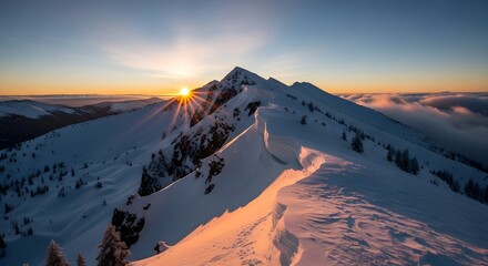 Snow covered mountain ridge at sunrise with sunburst and cloud inversion