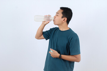 Thirsty Asian man drinking water from reusable bottle for hydration