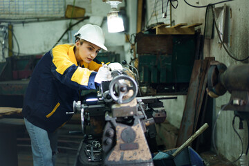 Female engineer inspecting and repairing metal lathe machine.