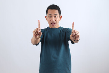 Excited Asian man pointing fingers up making number one gesture