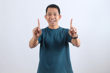 Happy excited Asian man pointing fingers up isolated on white background
