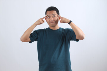 Thinking Asian man pointing at temples, smart idea gesture.