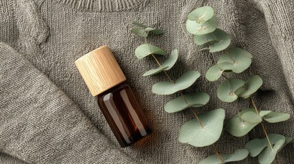 Natural Eucalyptus Leaf and Small Amber Glass Bottle on Soft Grey Fabric