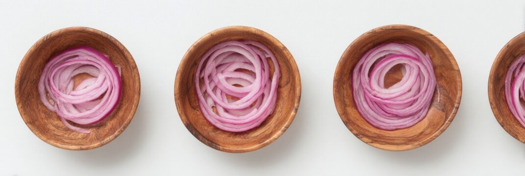 Thinly sliced red onions in three small wooden bowls, arranged in a row on a white background