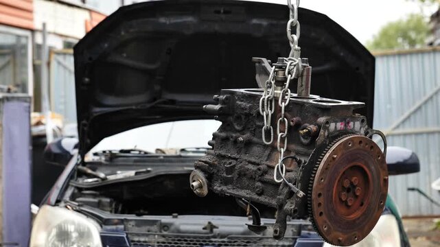 Car engine block hanging from chain for repair