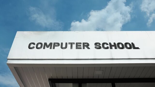 Computer School word sign clearly displayed on the educational facility facade beneath a clear blue sky, signifying an institution dedicated to teaching programming, IT skills, digital literacy