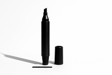 Black marker standing upright on its cap with a short straight black swatch drawn beneath studio isolated on white