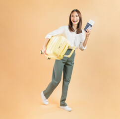 Happy Asian business woman holding suitcase and passport with plane tickets and credit card on beige color background. Tourist travel trip journey concept.