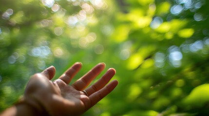 A hand reaches out towards a vibrant, green backdrop, capturing a serene moment in nature with a soft, blurred focus.